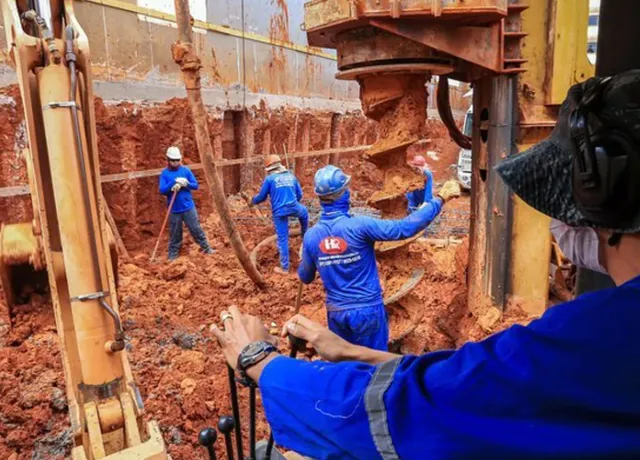Trado escavando estaca em obra da HR Fundações em Brasília, com equipe posicionando a armadura