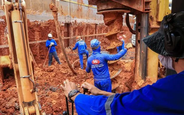 Trado escavando estaca em obra da HR Fundações em Brasília, com equipe posicionando a armadura